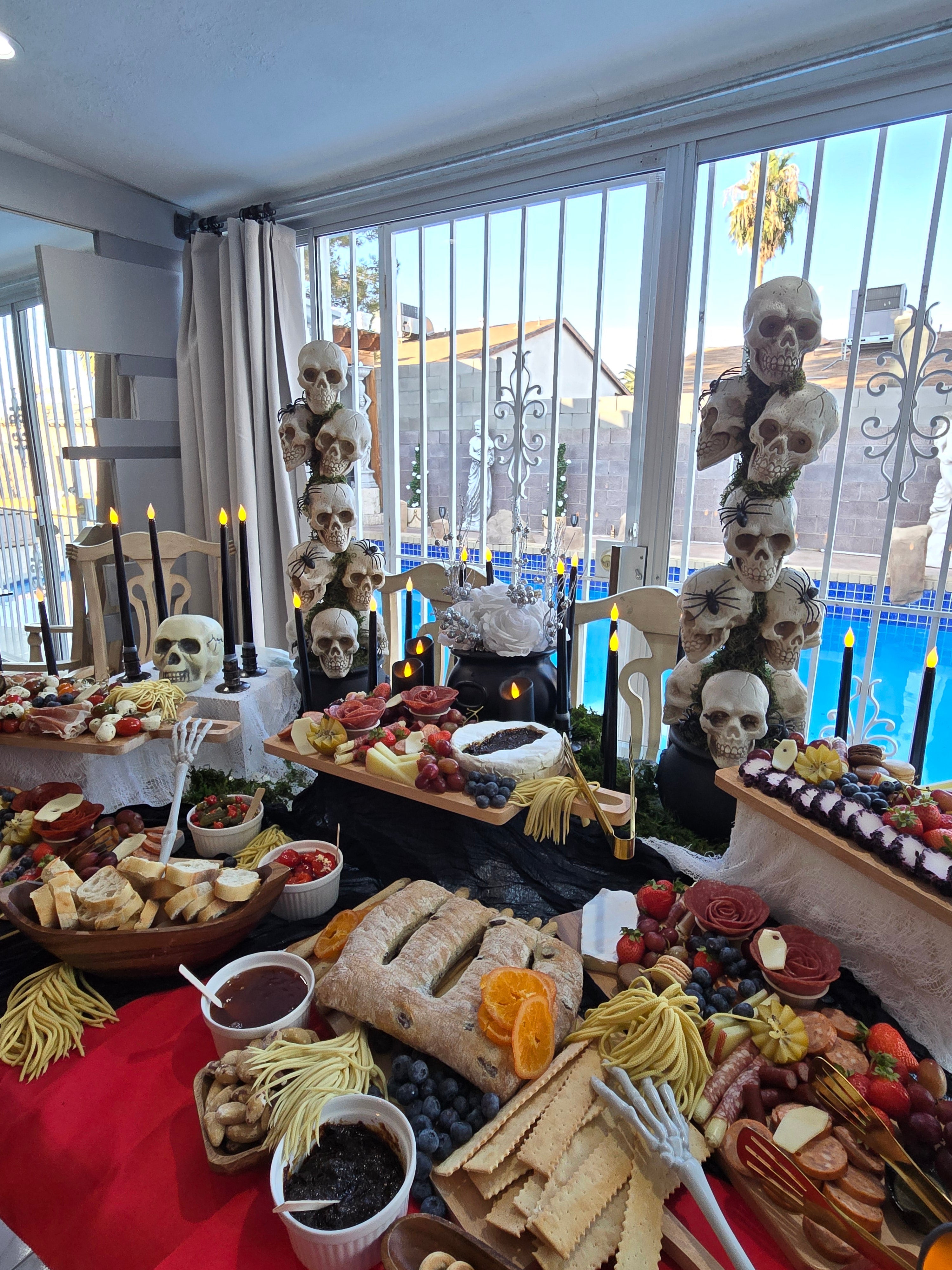 Spooky Halloween grazing table with charcuterie, cheeses, and skull decorations.