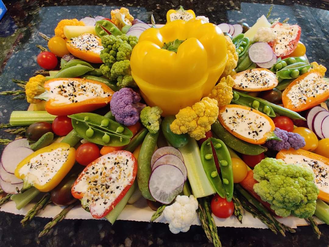Colorful vegetable platter with stuffed mini peppers, cauliflower, and fresh garden veggies.